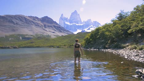 Young-woman-walking-in-the-lake-in-Laguna-Carpi,-looking-at-the-Fitz-Roy-in-Patagonia,-Argentina