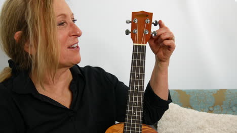 Woman-explaining-the-parts-of-the-ukulele-guitar,-smiling,-handheld