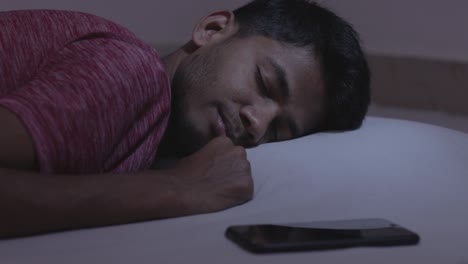 Concept-showing-of-irregular-sleep-or-sleep-deprivation-caused-due-to-mobile-phone,-young-adult-got-the-message-while-sleeping-causing-disturbance-and-affects-the-sleep-and-health