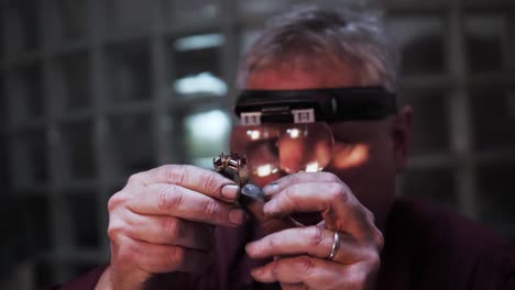 Old-man-inspecting-an-expensive-big-gold-ring-with-stones-in-slow-motion