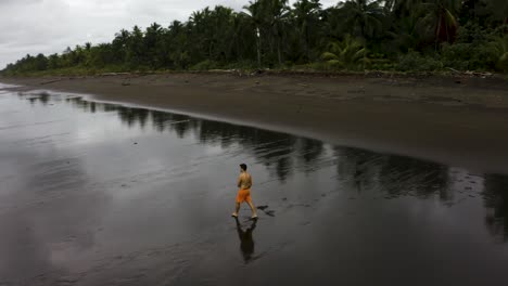 Aerial-of-a-young-man-that-makes-a-backflip-on-empty-beach,-Colombia