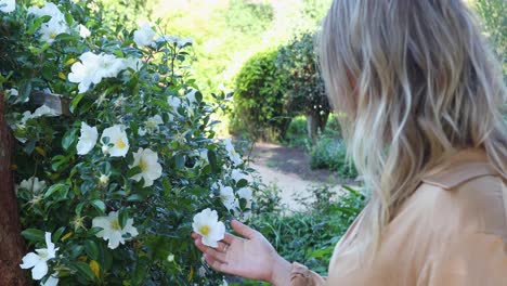 Young-woman-coresses-white-flower-in-garden_slow-motion