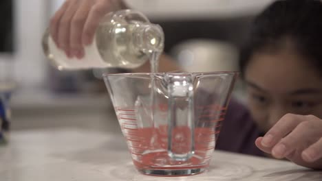 A-young-Korean-girl-pours-syrup-into-a-measuring-cup-while-baking-cookies