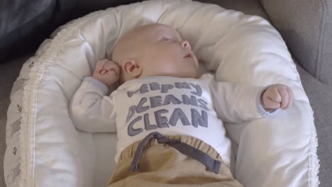 Closeup-baby-lying-content-in-cot-pram-wearing-clean-ocean-t-shirt