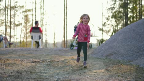 Static,-slow-motion-shot-of-a-little-blonde-girl-running-in-a-finnish-forest,-with-a-stick-in-her-hand,-on-a-sunny-spring-day,-in-Vaasa,-Ostrobothnia,-Finland
