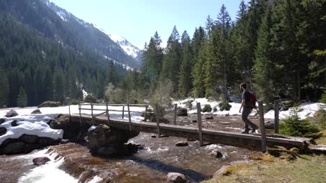 Still-shot-of-a-young-man-walking-over-a-bridge-on-a-valley-in-the-Swiss-Alps-in-slow-motion