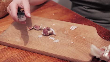 Woman's-hands-peeling-garlic-on-a-chopping-board