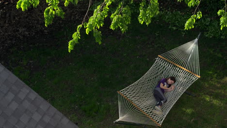 A-girl-rests-in-a-hammock-as-an-aerial-camera-rises-above-her