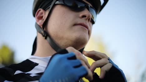 A-man-wearing-sunglasses-buckling-up-his-bicycle-helmet-in-preparation-to-go-cycling