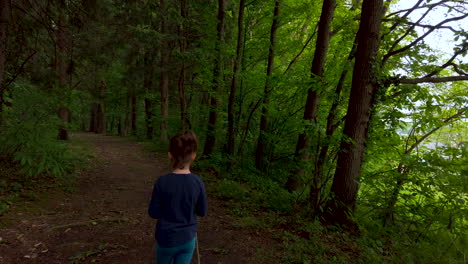 Closeup-of-a-little-girl-walking-on-a-footpath,-alone-in-dark,-spooky-forest