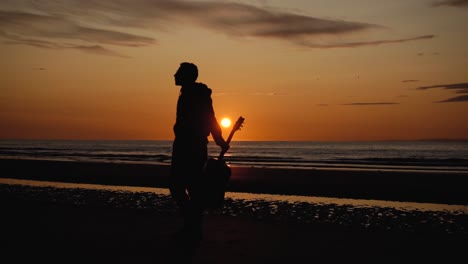 Man-running-with-guitar-in-back-sand-beach-at-sunset-36