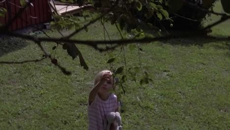 Slow-motion-shot-of-girl-trying-to-pick-cherry-berries-from-tree-in-high-wind,-masking-effect-possible