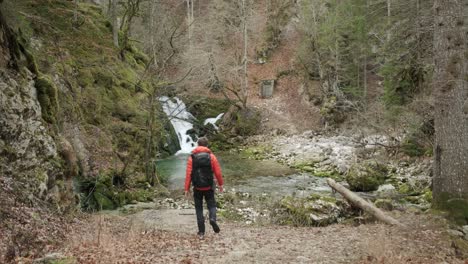 Man-walking-towards-the-river-and-waterfall