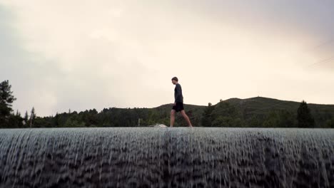 Man-walking-on-top-of-a-dam-in-Norway,-Europe-4K