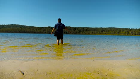 Male-tourist-walking-into-the-brown-lake,-north-stradbroke-island,-Queensland,-Australia-1