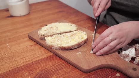 Woman's-hands-puts-garlic-on-a-second-slice-of-bread-with-butter