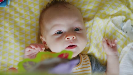 Entzückendes-Baby-Lacht-Und-Kichert-Beim-Spielen-Unter-Ihren-Hängenden-Spielzeugen-Auf-Einer-Gelben-Decke