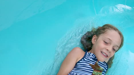 Close-up-of-smiling-young-girl-going-down-a-water-slide