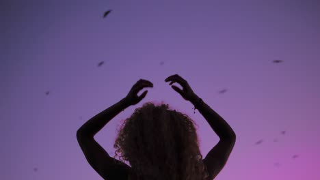 Silhouette-Of-A-Gorgeous-Lady-Dancing-Gracefully-Under-The-Purple-Sky-During-Sunset-With-Bats-Flying---Close-up-Shot