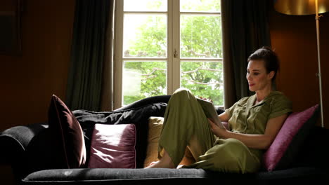 Woman-Sitting-in-Sofa-Checking-Tablet,-Boudoir-Scene-Sliding-Shot