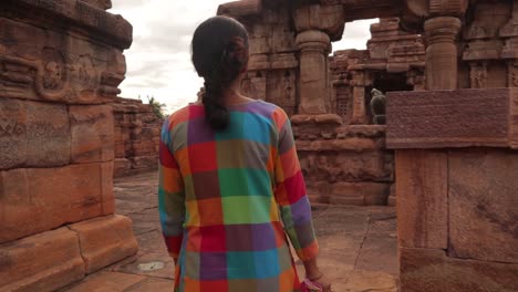 Medium-close-up-shot,-Back-view,-following-a-Tourist-girl-from-behind-at-ancient-temple-ruins-of-India---Woman-walking-alone-at-ruined-archeological-site