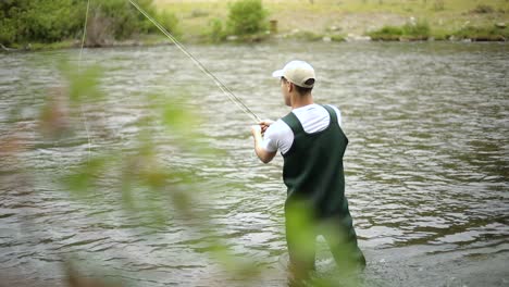 Shot-of-a-Caucasian-male-fisherman-casting-his-hook-while-Fly-Fishing-4