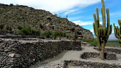 A-woman-takes-a-photograph-of-the-ruins-and-landscape-at-the-ancient-city-of-Quilmes,-an-archaeological-site-in-the-Calchaquí-Valleys,-Argentina