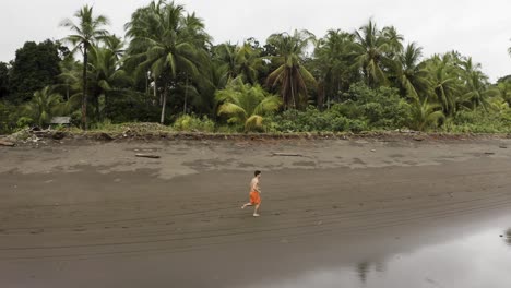Aerial-follows-a-young-man-jogging-at-an-empty-beach-in-Choco,-Colombia