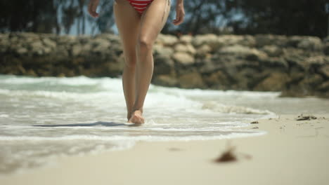 Woman-in-a-red-bikini-walking-along-a-beach-in-Australia