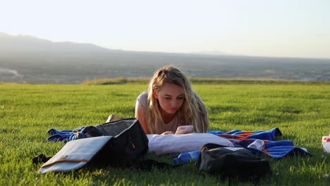 Shot-of-a-beautiful-young-woman-laying-on-a-blanket-on-the-grass-at-a-park