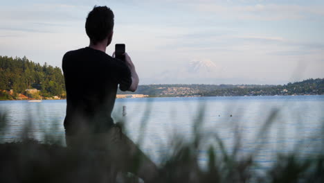 Static-shot-of-young-man-taking-pictures-and-selfies-with-a-cell-phone-in-front-of-Mt
