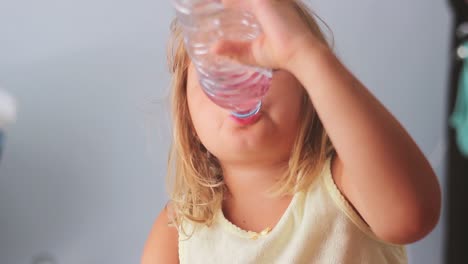 Cute-little-girl-is-opening-a-bottle-of-water-and-drinking