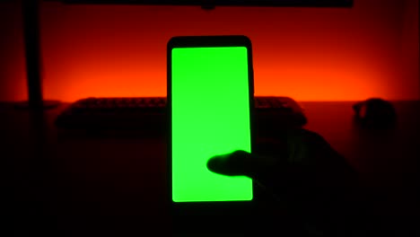 Green-screen:-right-thumb-scrolling-on-cellular-phone-in-dark-room-with-red-background-light