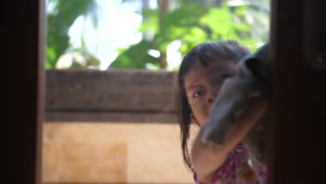 Hübsches-Kleines-Indonesisches-Kind,-Das-Mutter-Im-Haus-Hilft,-Indem-Es-Die-Fenster-In-Einer-Tür-Wäscht