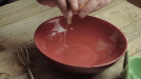Cracking-an-egg-into-a-red-bowl-ready-for-mixing