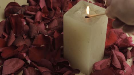 Lighting-a-candle-with-Red-rose-flower-petals-background