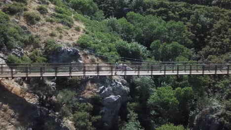 Drone-Shot-following-an-active-man-running-on-an-outdoor-hanging-suspension-bridge-above-Bear-Canyon-in-Draper-City,-Utah-1