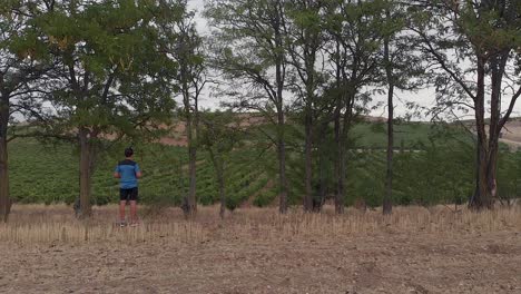 Man-walking-on-a-road-between-vineyards-and-trees-1