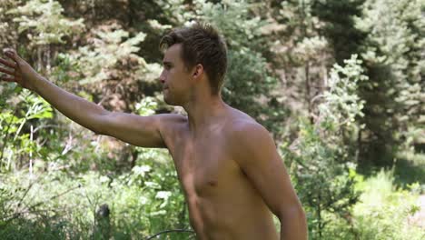 Slow-motion-shot-of-a-shirtless-man-practicing-his-axe-throwing-skill-by-trying-to-throw-his-hatchet-at-a-pine-tree-6