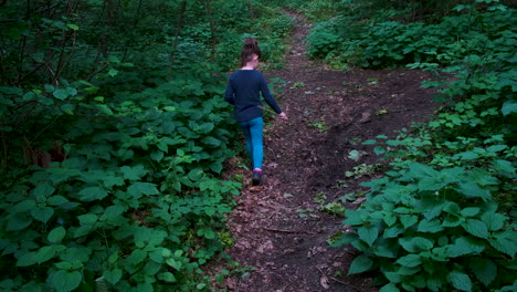 Little-girl-walking-on-a-footpath,-alone-in-dark,-spooky-forest