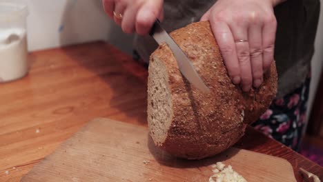 Woman's-hands-cut-slices-of-round-bread-on-a-chopping-board
