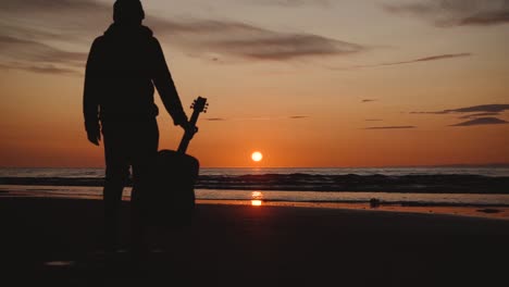 Man-running-with-guitar-in-back-sand-beach-at-sunset-14