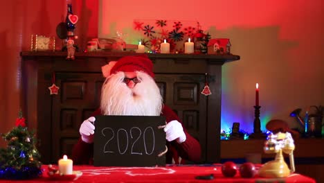Weihnachtsmann-Zeigt-2020-Notiz-Auf-Schwarzer-Tafel