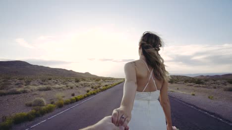 Bride-walking-down-road-holding-husband's-hand-in-slow-motion