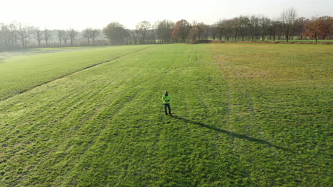 Aerial-drone-shot-flying-away-from-man-standing-in-the-field