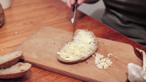 Woman's-hands-puts-garlic-on-slice-of-bread-with-butter