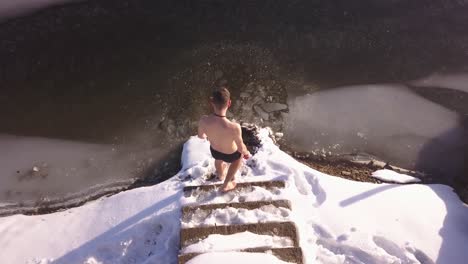 Man-about-to-enter-frozen-lake-slips-on-slick-snow-covered-steps