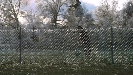SLOW-MOTION:-A-man-kicks-a-soccer-ball-into-an-icy-fence-which-explodes-the-shattered-ice-into-the-air