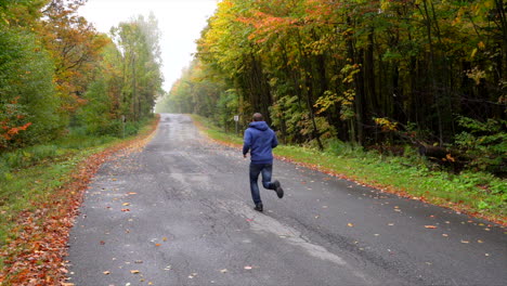 Man-running-on-a-small-road-surrounded-by-maple-autumn-maple-leaf-slowmotion-1
