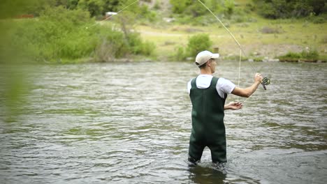 Slow-Motion-Shot-of-a-Caucasian-male-fisherman-casting-his-hook-while-Fly-Fishing-7